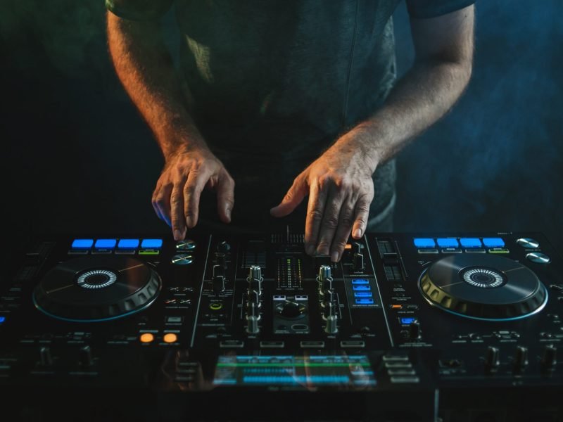 A closeup of a DJ working under the lights against a dark background in a studio